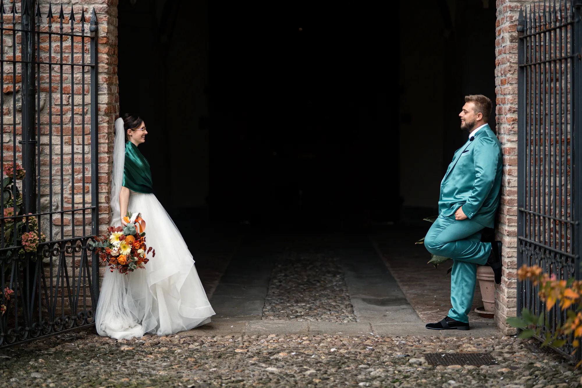 Sposi sotto un arco in pietra, lei con scialle verde e lui in abito verde