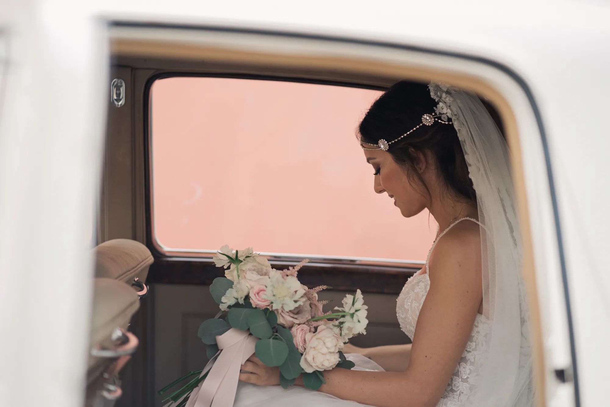 Sposa affacciata dal finestrino di un'auto d'epoca