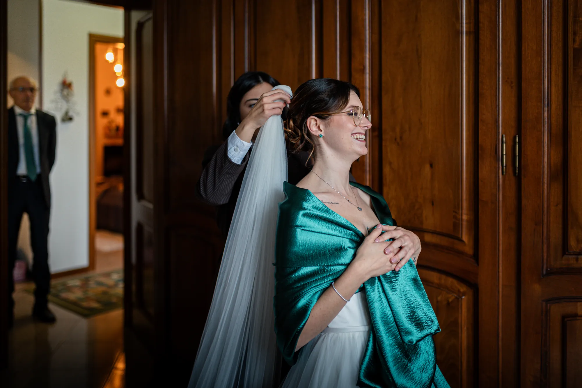 Sposa che sorride mentre le sistemano il velo, scialle verde